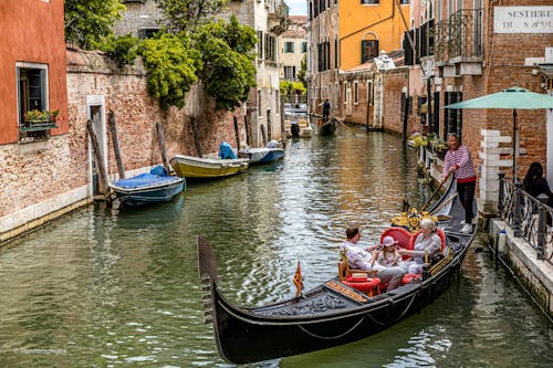 People on Gondola on Canal in Venice in Italy