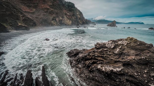 Stunning view of the rugged Bizkaia coastline with crashing waves and misty cliffs.