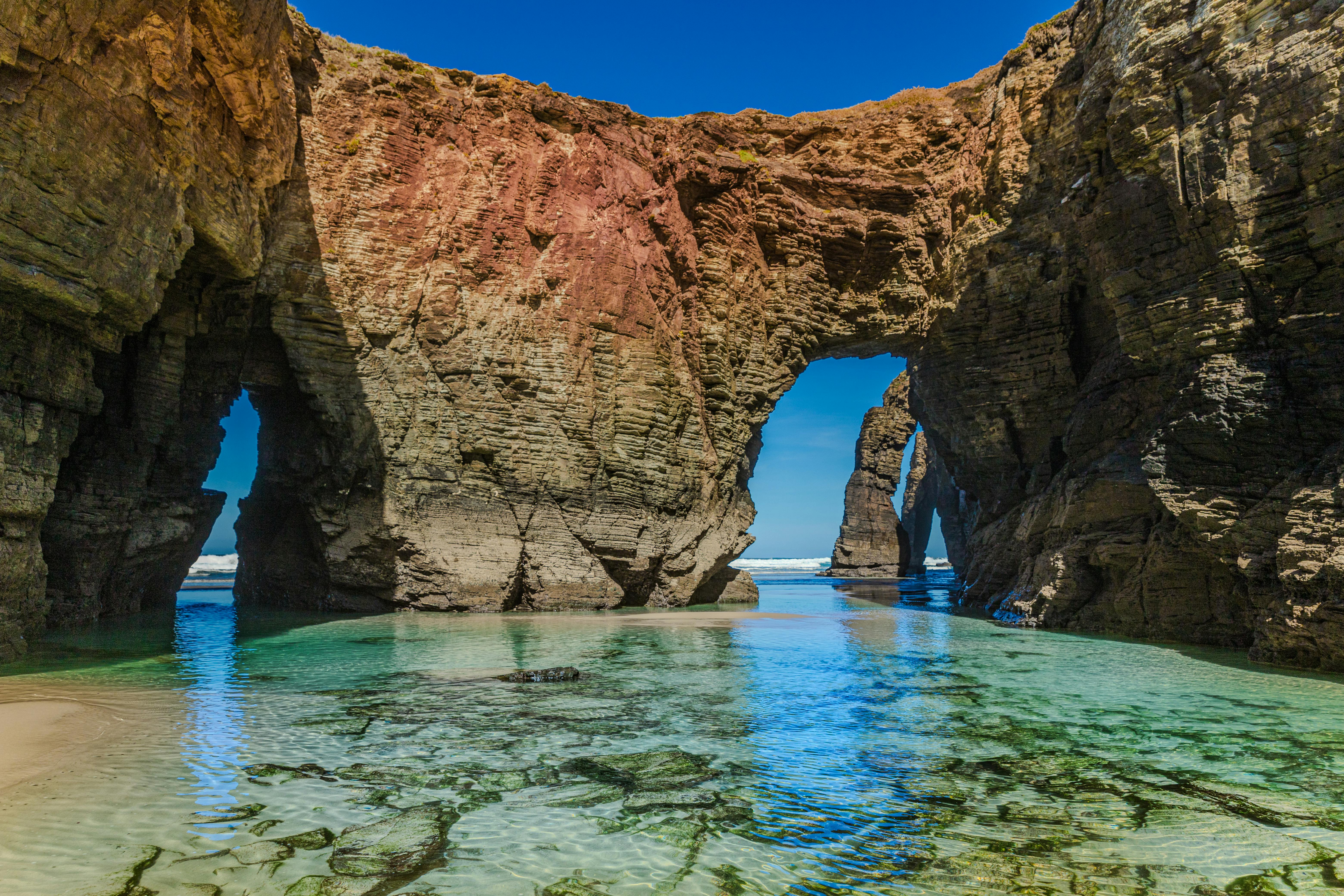 Dramatic rock formations and clear waters at A Rochela, a stunning beach in Spain. - Ribadeo