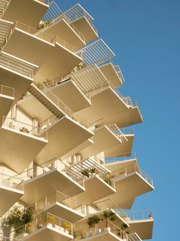 A unique architectural design featuring numerous large balconies against a clear blue sky.