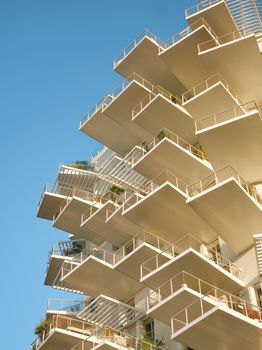 Striking geometric architecture featuring layered balconies against a clear blue sky.