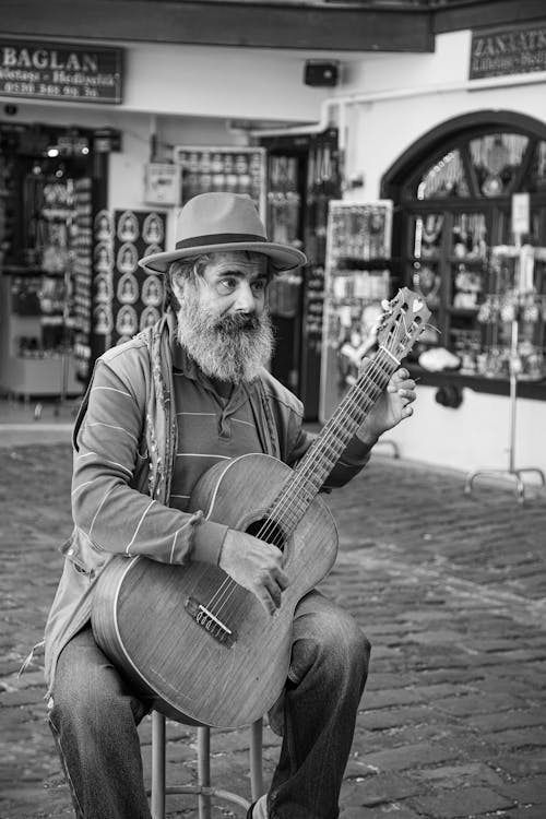 A man with a beard and hat playing guitar