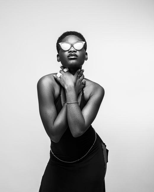 Elegant black and white portrait of a confident woman wearing sunglasses, exuding style and grace.