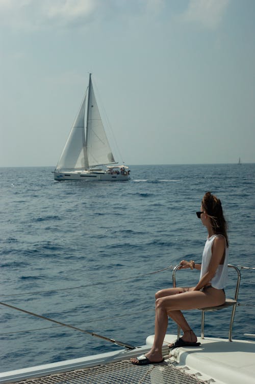 A woman sitting on the edge of a boat looking out to sea