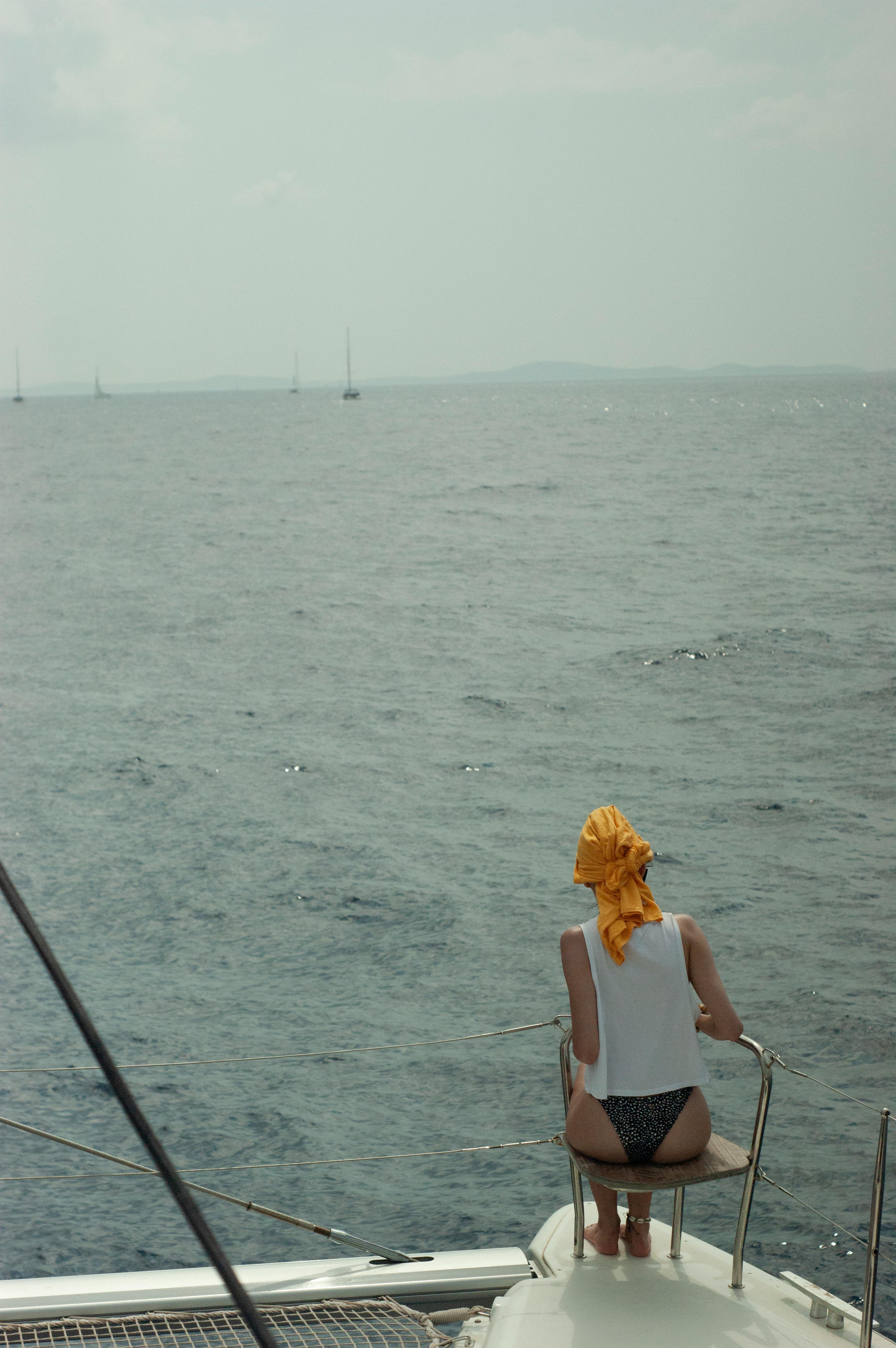 A woman sits on a yacht enjoying a sunny day at sea. Perfect for travel and lifestyle imagery.