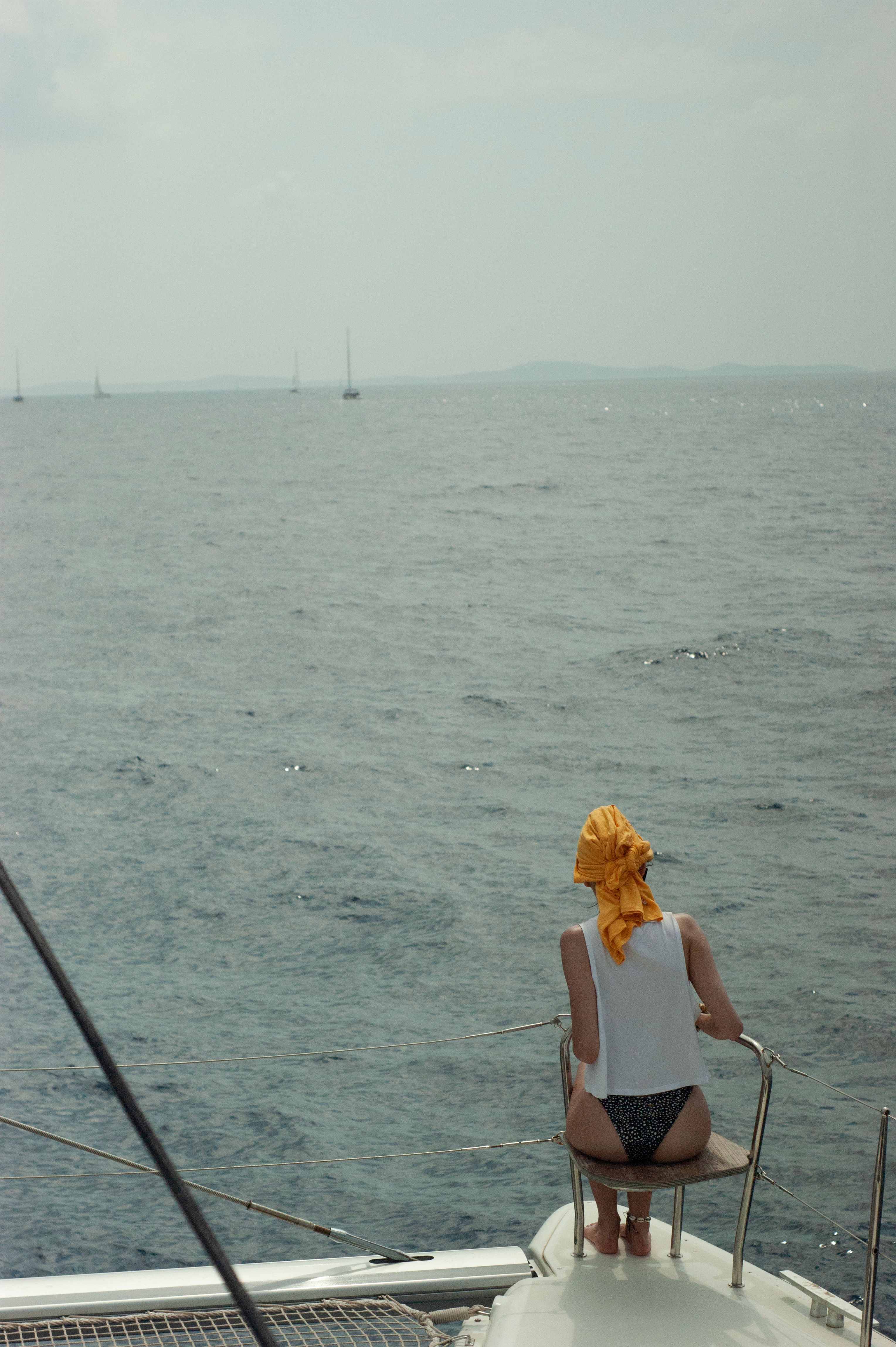 A woman sitting on the back of a boat looking out to sea · Free Stock Photo