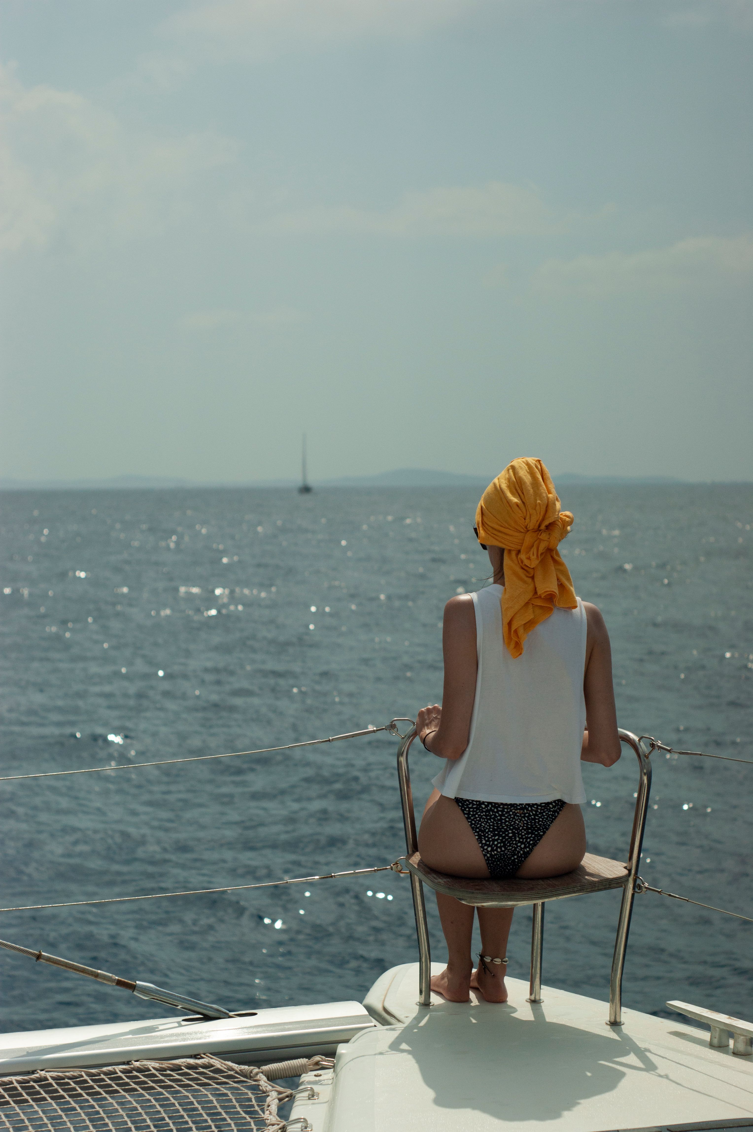 Uma mulher em traje de verão desfruta de uma relaxante viagem de iate com uma deslumbrante vista do oceano.