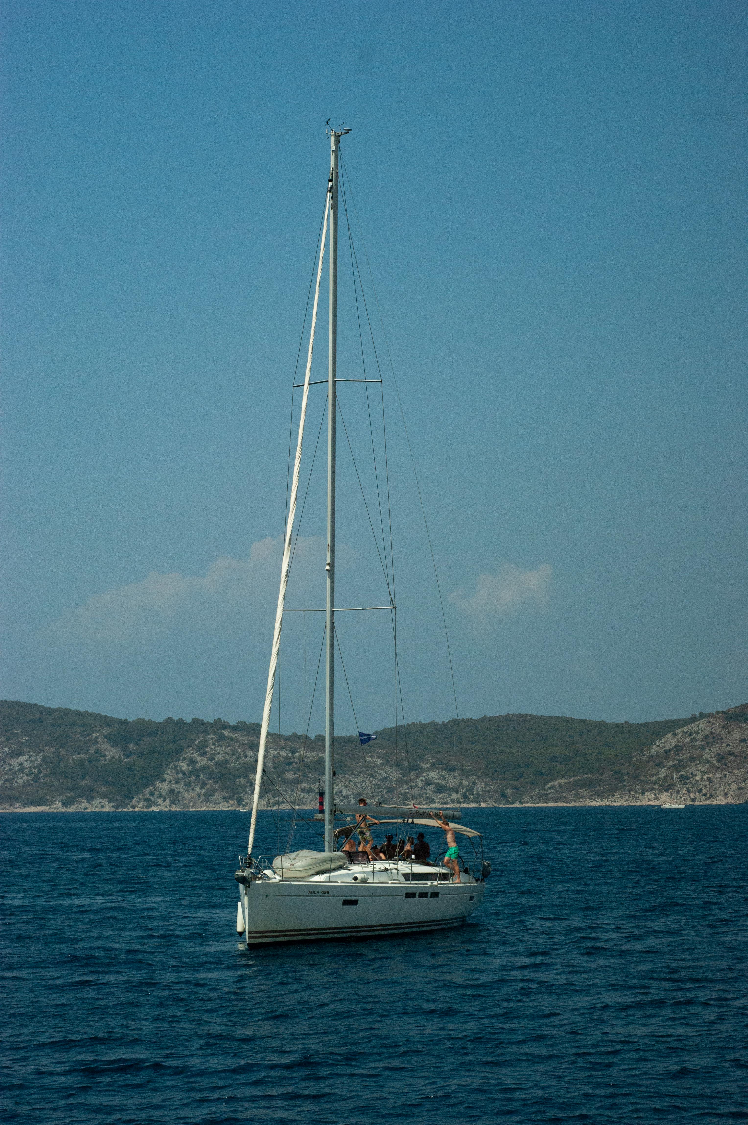 Sailboat cruising on a sunny day with clear water and hills in the background. Perfect for summer travel lovers.
