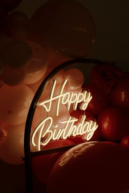 Neon 'Happy Birthday' sign with vibrant balloons setting a festive mood.
