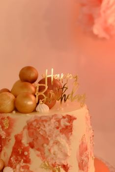 A stylish birthday cake with gold decorations and a 'Happy Birthday' topper.