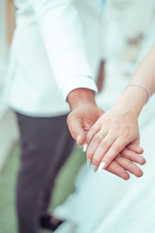 Free Close-up of a couple holding hands in wedding attire, symbolizing love and unity. Stock Photo