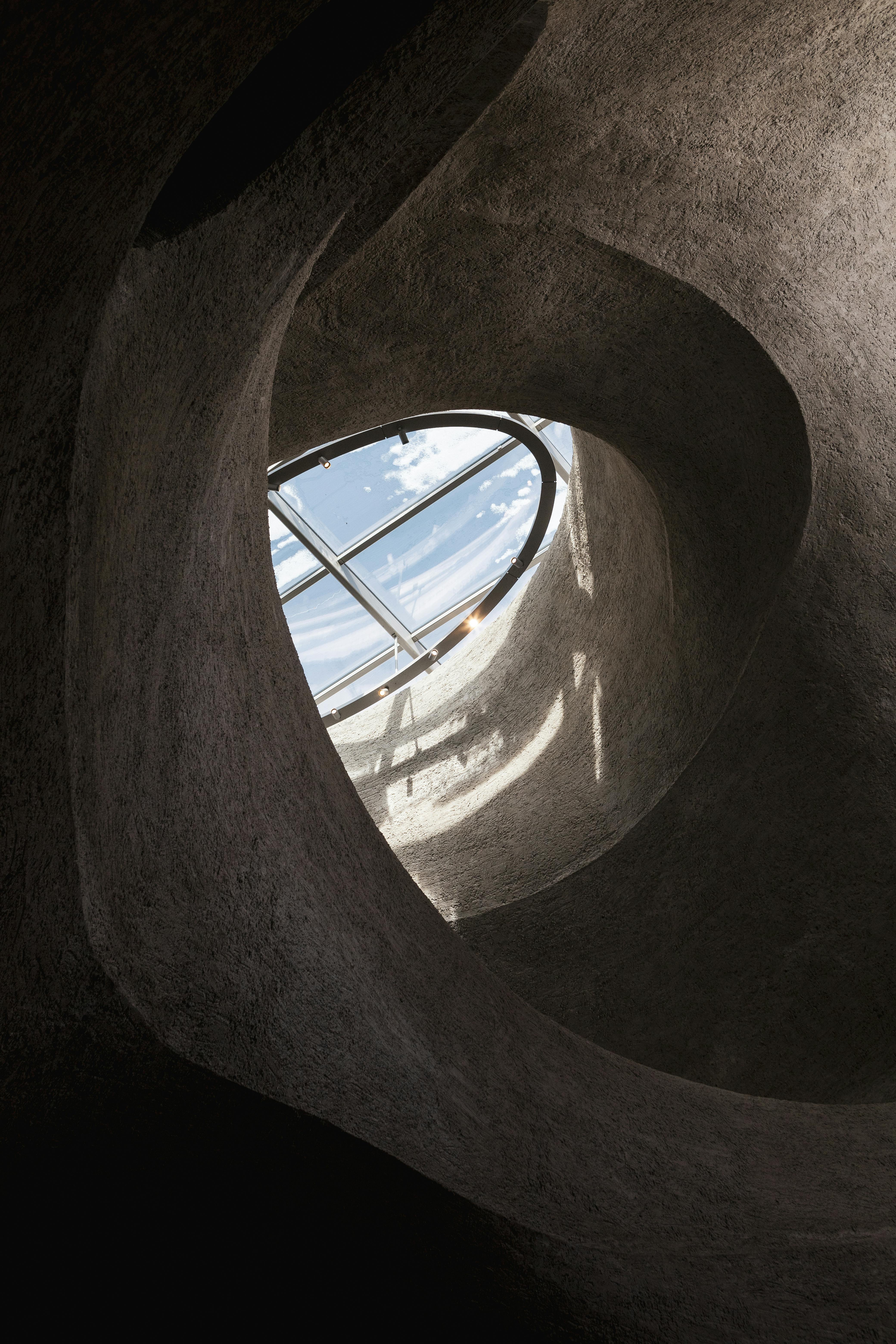 Curved architecture framing a skylight, capturing light and shadow play.