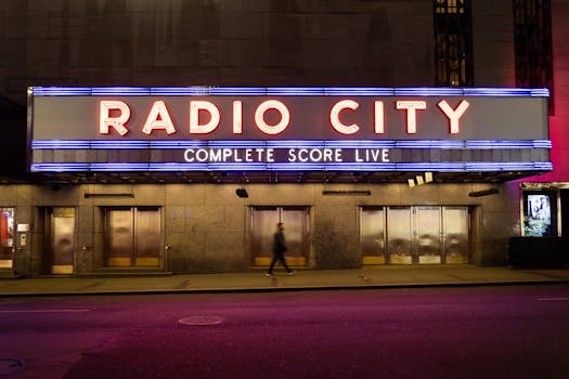 Captured at night, Radio City Music Hall neon lights glow vividly on a quiet NYC street.