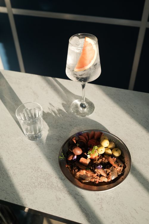 Free A stylish high-angle shot of a cocktail and meal with natural light on a modern table. Stock Photo