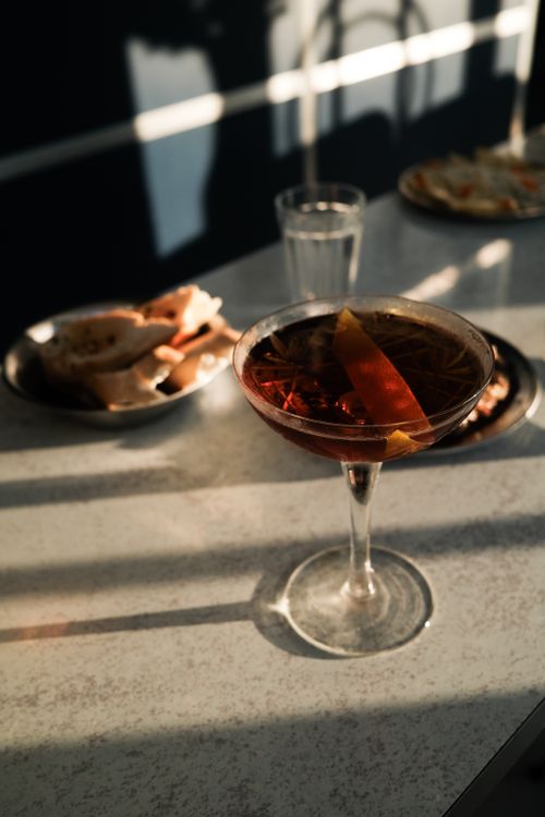 Free A refreshing cocktail with citrus garnish on a sunlit table, perfect for a relaxing afternoon. Stock Photo