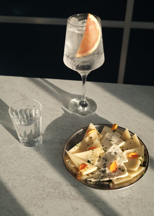 Free Elegant cheese platter and gin tonic with grapefruit slice, perfect for a sunny afternoon. Stock Photo