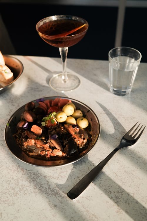 Free A well-presented gourmet meal served with a cocktail and water on a modern dining table. Stock Photo