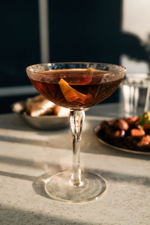 Free Close-up of an elegant whiskey cocktail with orange peel, captured in a sunlit indoor setting. Stock Photo