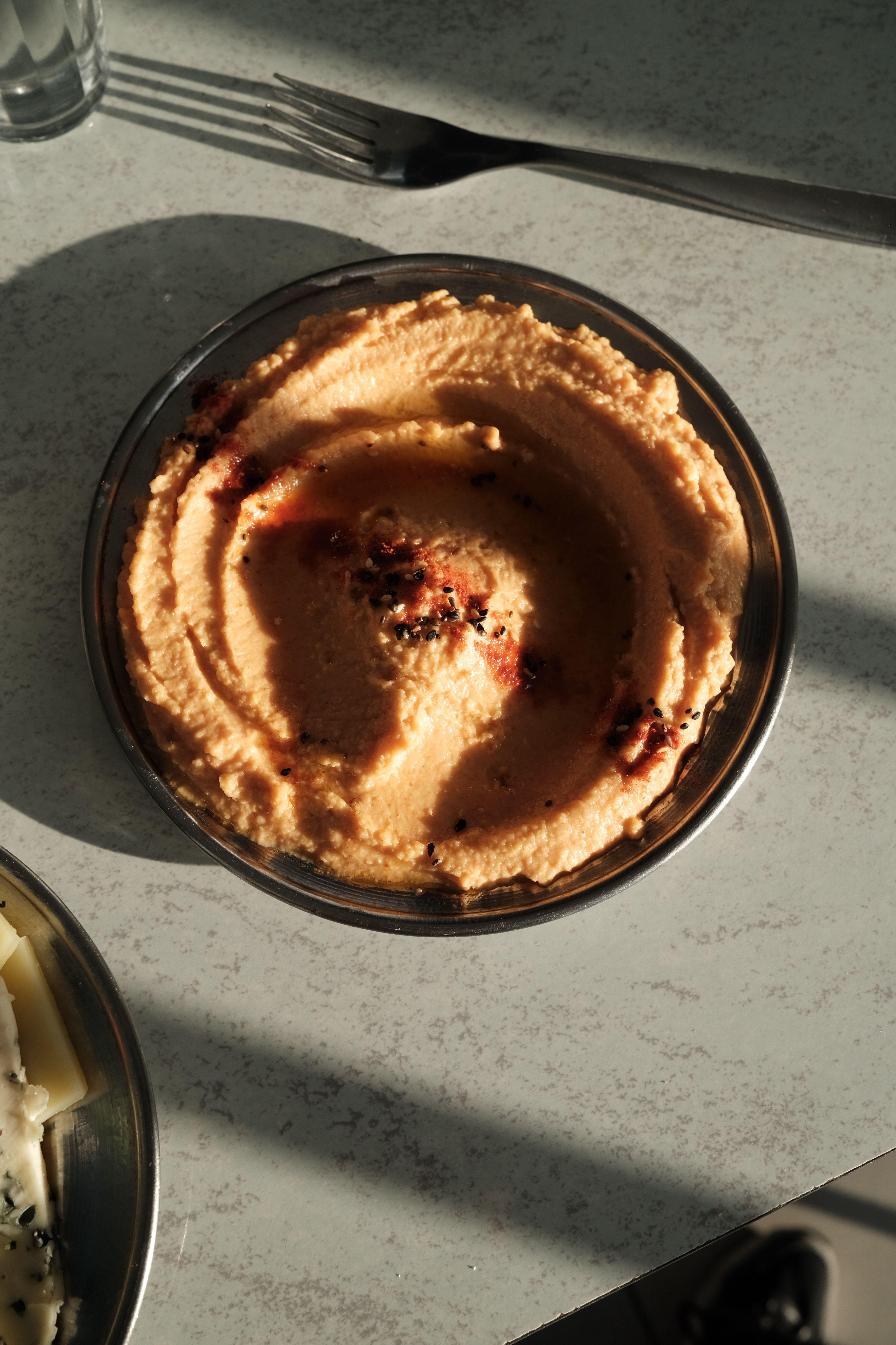 Close-up of creamy hummus in a bowl, surrounded by subtle shadows, perfect for food photography.