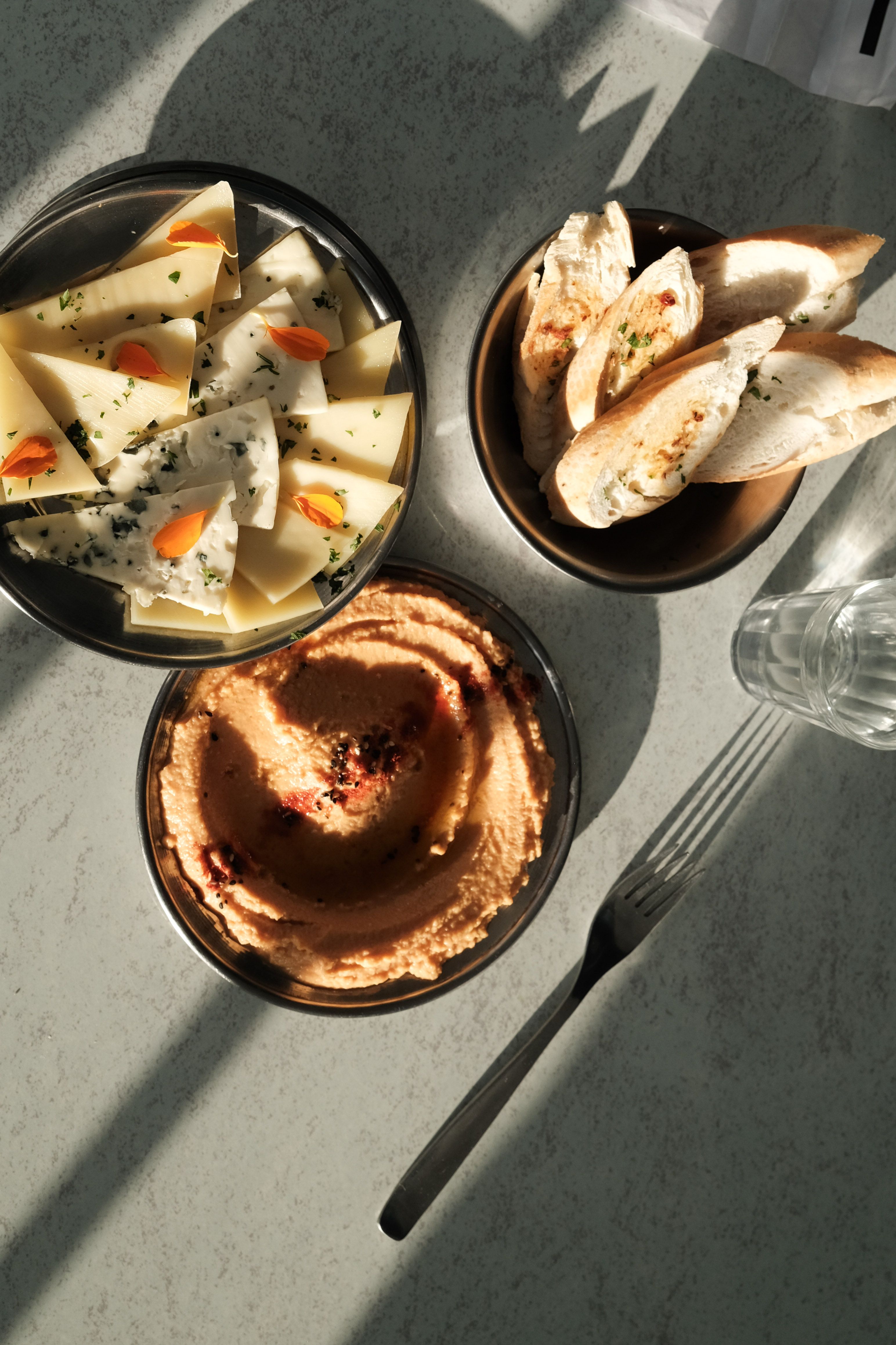 A gourmet delicacy of cheese, bread, and hummus served in natural light, perfect for brunch.