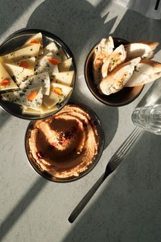 A gourmet delicacy of cheese, bread, and hummus served in natural light, perfect for brunch.