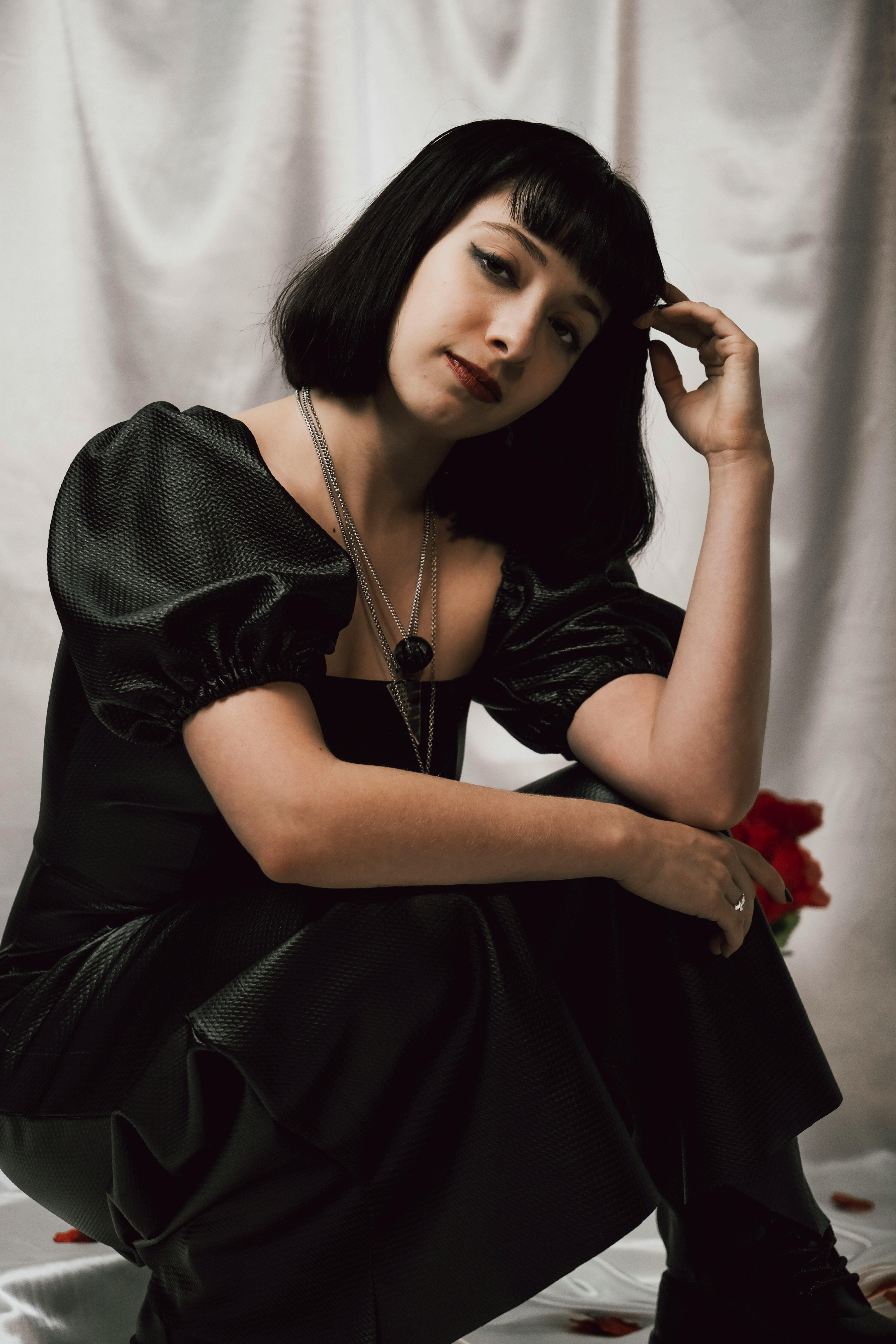A chic young woman in black gothic style posing against a white background.
