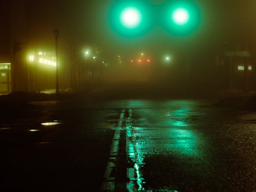A street with green lights and fog