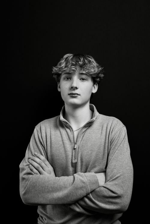 Free Black and white portrait of a young man with folded arms in a studio setting. Stock Photo