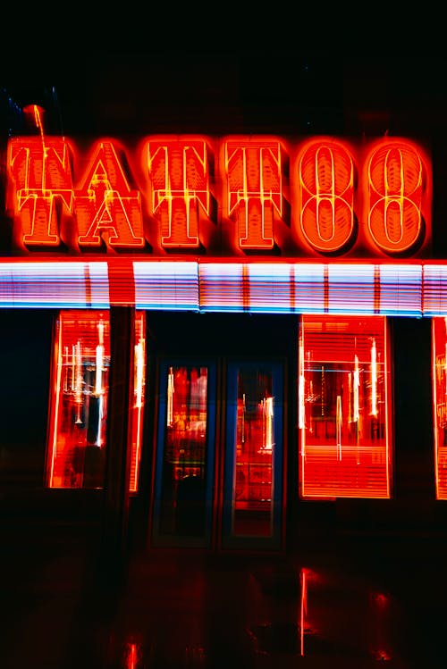 A neon sign for a tattoo shop in the dark