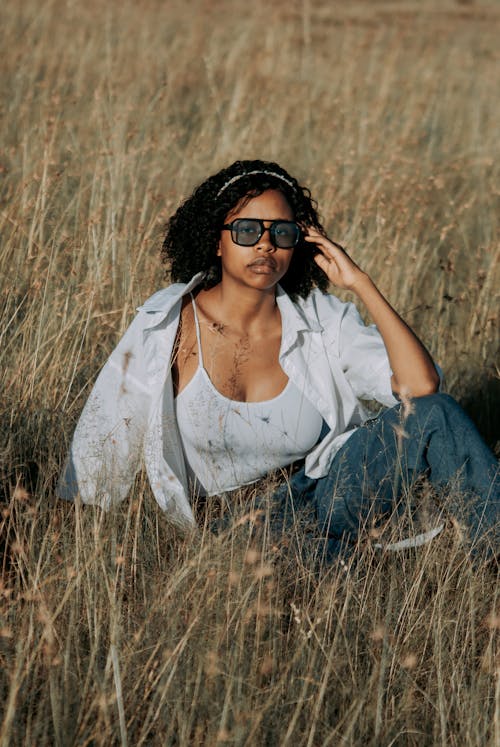 A woman in sunglasses sitting in a field