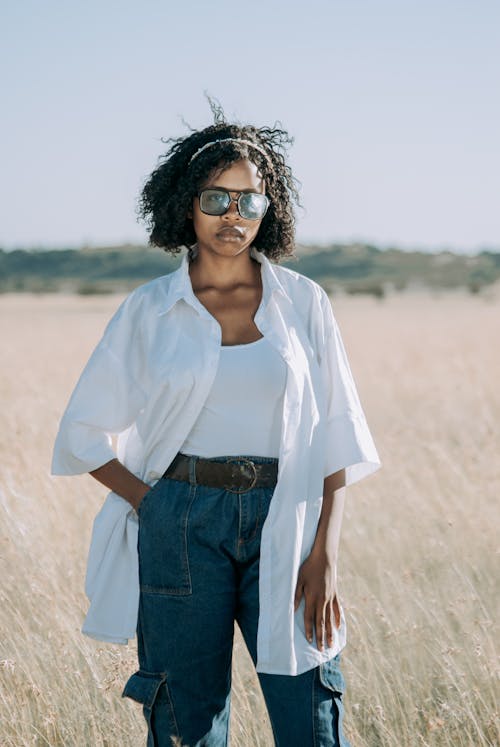 Woman with Sunglasses in White Shirt Posing in Field