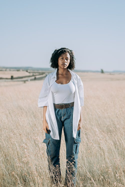 Woman in White Shirt and Jeans Standing on Field