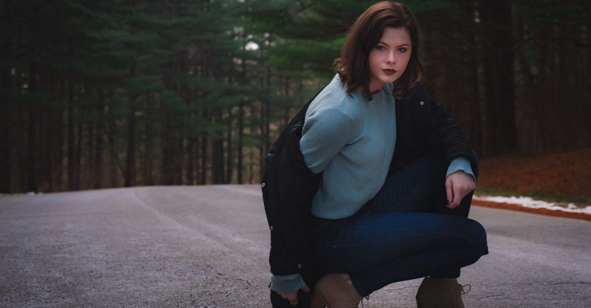 Woman in stylish winter attire posing on a forest road in Rockford, IL.