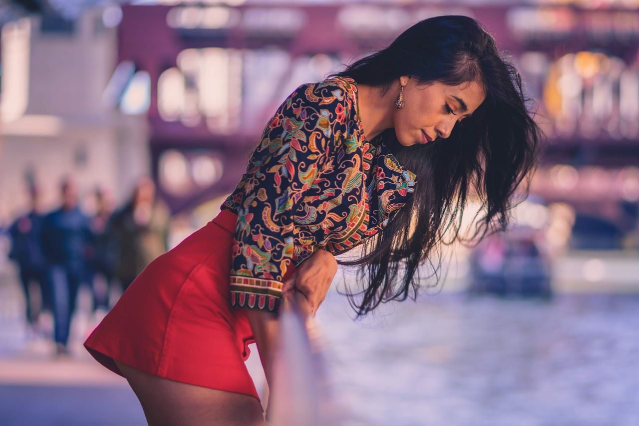 a fashionable woman in vibrant attire poses by the chicago river with