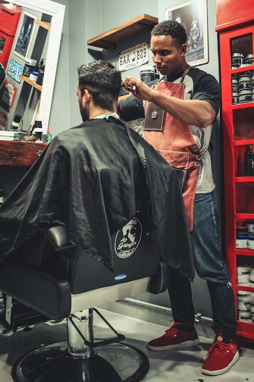 Мужчина стрижет волосы Мужчина сидит на стуле парикмахера