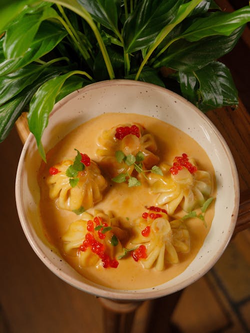 A bowl of soup with dumplings and peppers