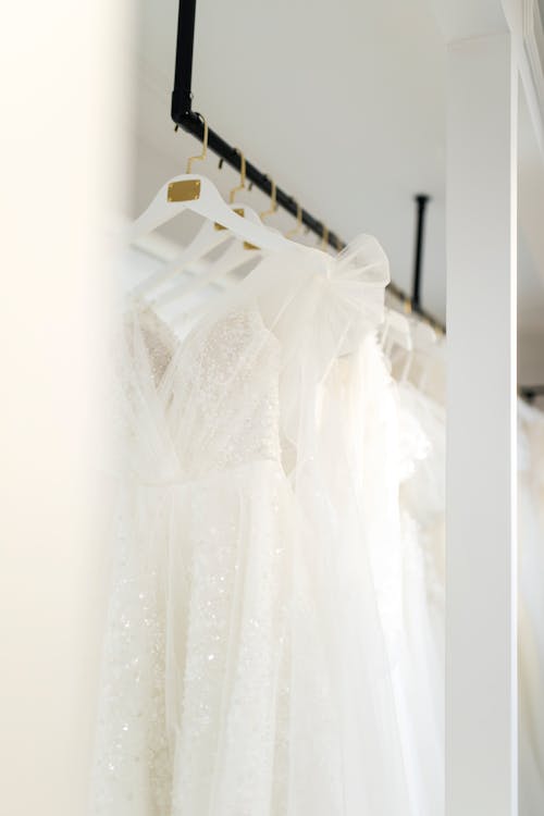 A wedding dress hanging on a rack in a closet