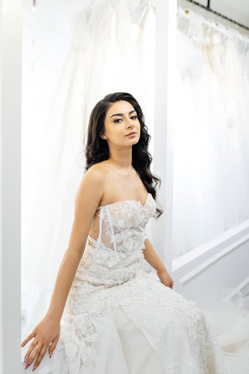 A woman in a wedding dress sitting in front of a mirror