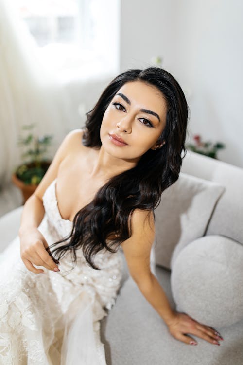 A beautiful woman in a wedding dress sitting on a couch