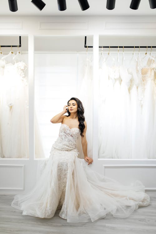 A woman in a wedding dress poses in front of a rack of wedding dresses