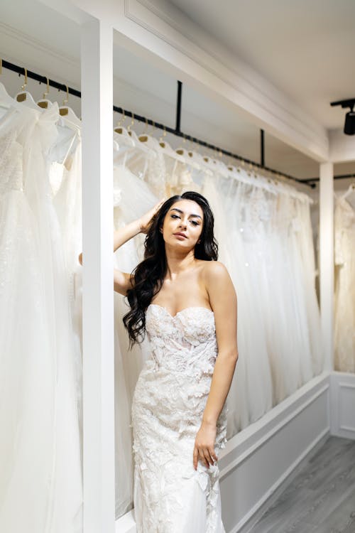 A woman in a wedding dress poses for a photo