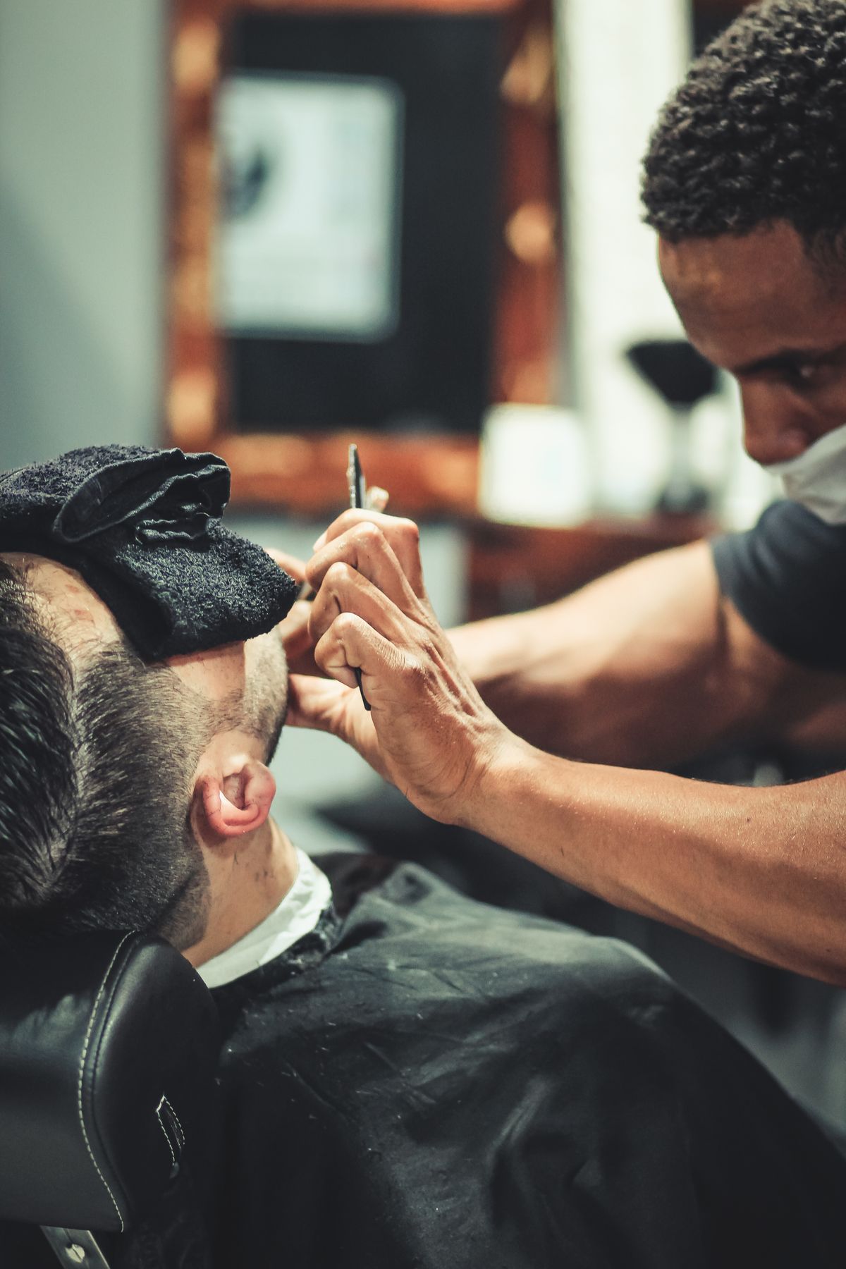 A barber detailing the side of a cut with shears