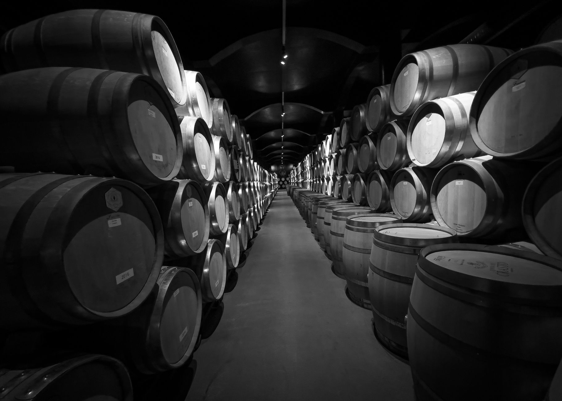 Black and white photo of wine barrels stored in a cellar at a Portuguese winery.