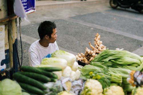 Free An Asian man selling fresh vegetables at a street market, captured with selective focus. Stock Photo