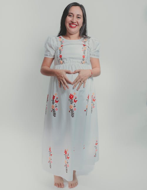 A pregnant woman in a white dress with flowers