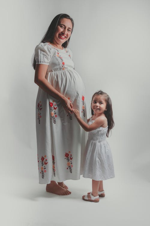 Smiling Mother Standing and Holding Hands with Daughter