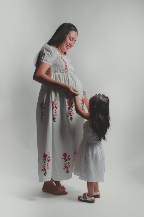 Smiling Pregnant Mother Standing with Daughter