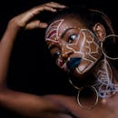 这幅非洲女性的肖像富有表现力，她脸上绘有复杂的彩绘，戴着大胆的耳环，象征着文化身份