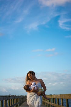 在晴朗的蓝天下，母亲在户外给孩子哺乳，这是一个美丽的母性时刻