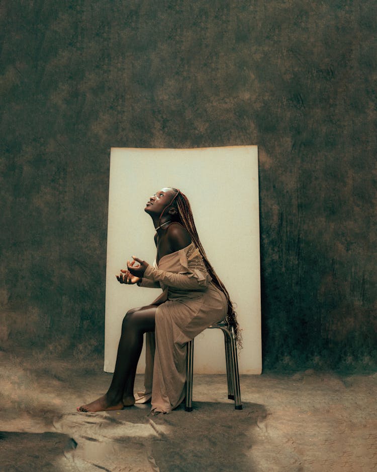 Woman In Dress Sitting On Chair And Looking Up